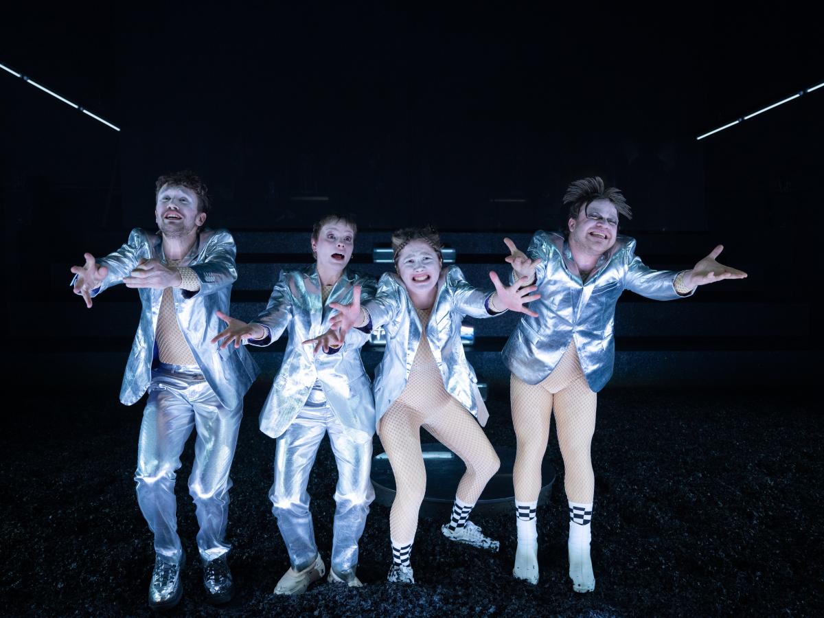 vier silber gekleidete Menschen strecken ihre Arme verzweifelt, glücklich, sehnsüchtig Richtung Fotograf