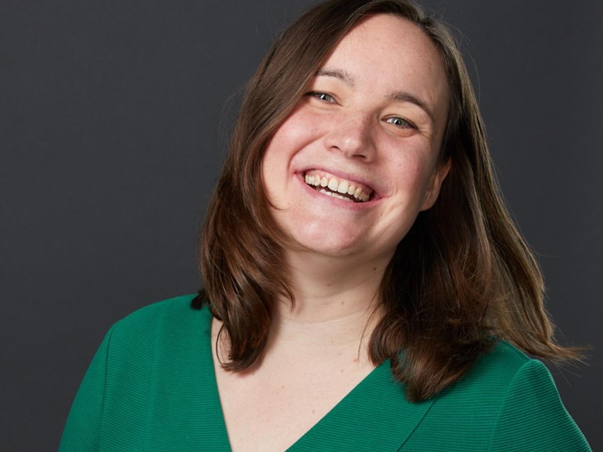 Portrait von Prof.in Dr. Judith Möller. Sie trägt ein grünes Oberteil, ihre Haare braun, leicht geschwungen, gehen ihr bis zur Schulter. Sie lacht und zeigt ihre Zähne.