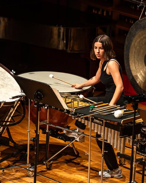 Studierende der Schlagzeugklasse sitzt in einem vielfältigen Setup aus Schlagzeuginstrumenten.