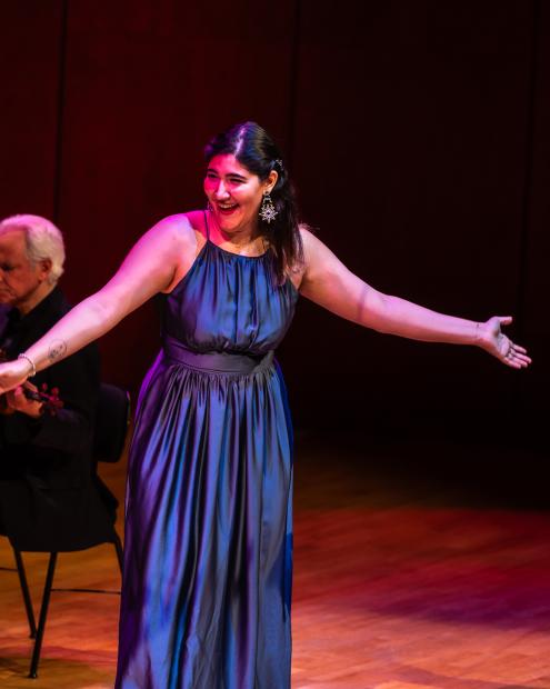 Sängerin im blauen langen Kleid breitet ihre Arme aus.
