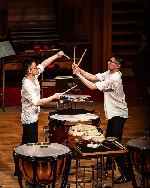 Schlagzeugstudierende schlagen erhobene Schlägel aneinander. Eine trennung erfahren sie durch einen Schlagaufbau.