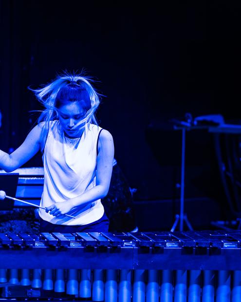 Studentin spielt Vibraphone in blauem Licht.