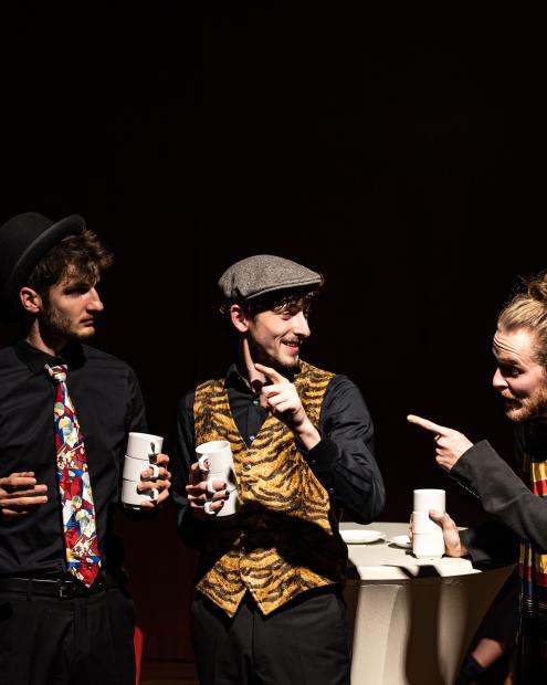 Drei Männer kommunizieren miteinander während sie je drei Tassen halten.