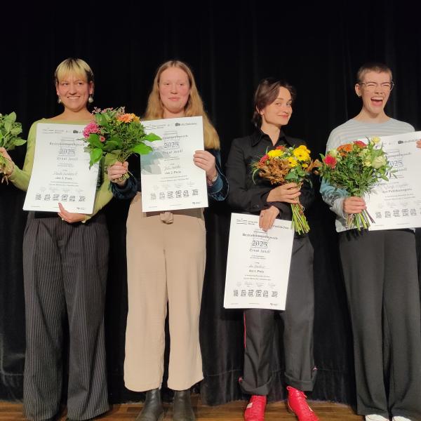 Foto von Gewinnerinnen des Rezitationswettbewerbs "Ernst Jandl". Die Gewinnerinnen stehen mit Urkunden und Blumensträußen auf der Bühne.