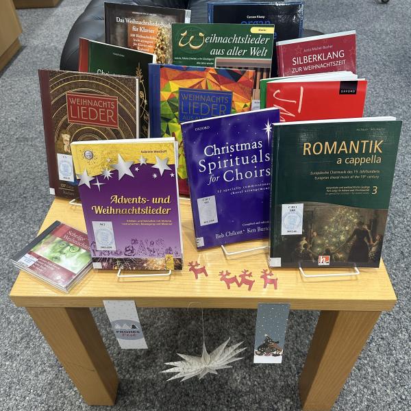 Das Bild zeigt verschiedene Noten zum Thema Weihnachten auf einem weihnachtlich dekorierten Tisch.