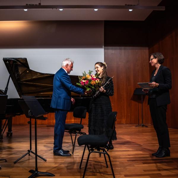 Übergabe des Blumenstraußes von dem Rektor Axel Köhler an die Stipendiatin Alessia Vermi auf der Bühne.