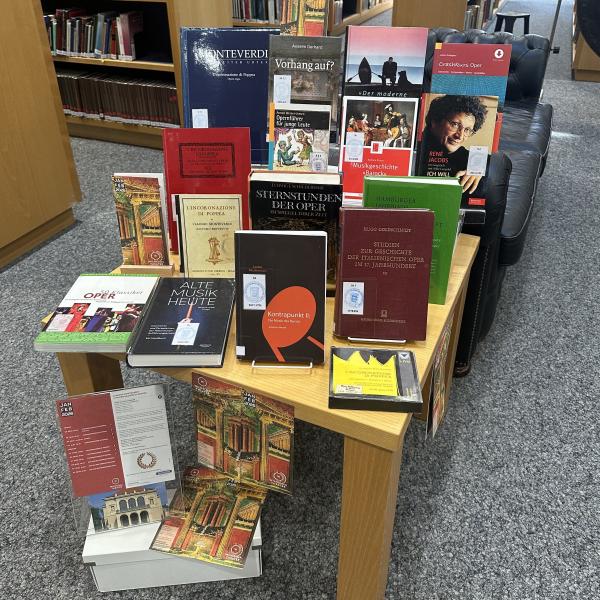 Das Bild zeigt Bücher und Noten zum Thema Barockoper auf einem Tisch in der Bibliothek.