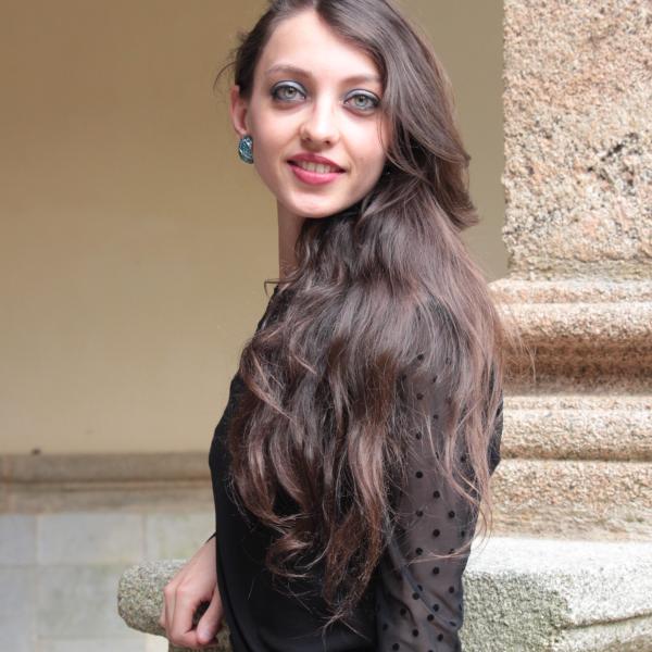 Bérénice Nuss steht an einer Steinmauer und schaut über die Schulter mit dem Blick zur/zum Fotograf*in.