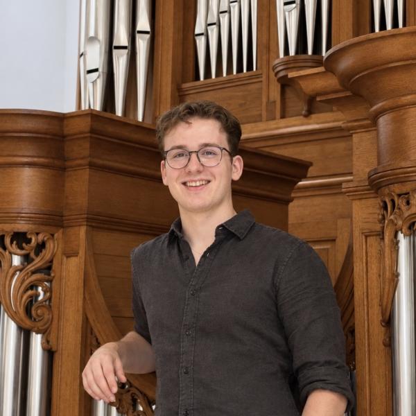 Portrait von Sebastian Schlosser vor einer Orgel stehend
