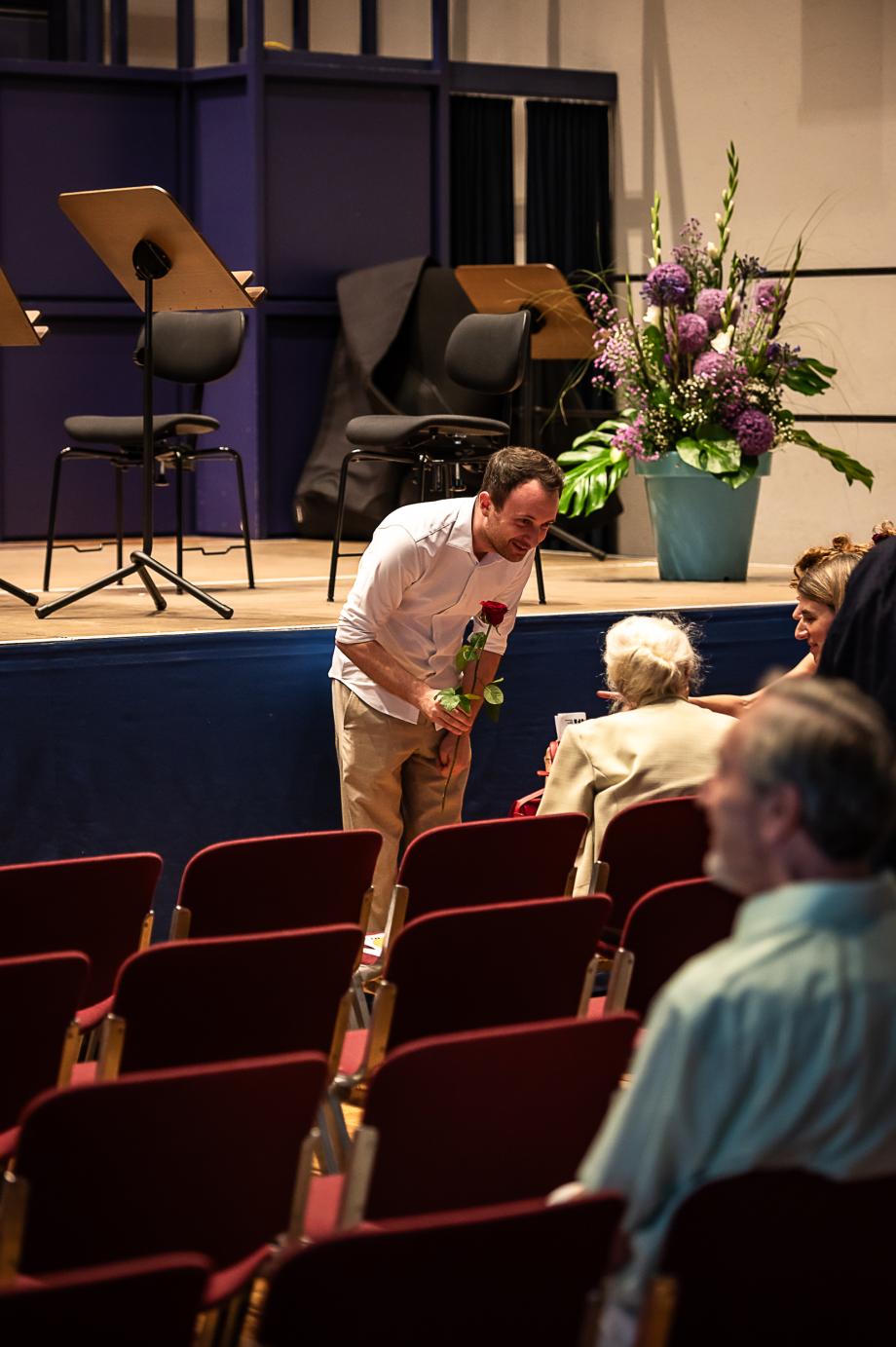 Student überreicht eine Rose an Gudrun Mehl von der ROM Stiftung
