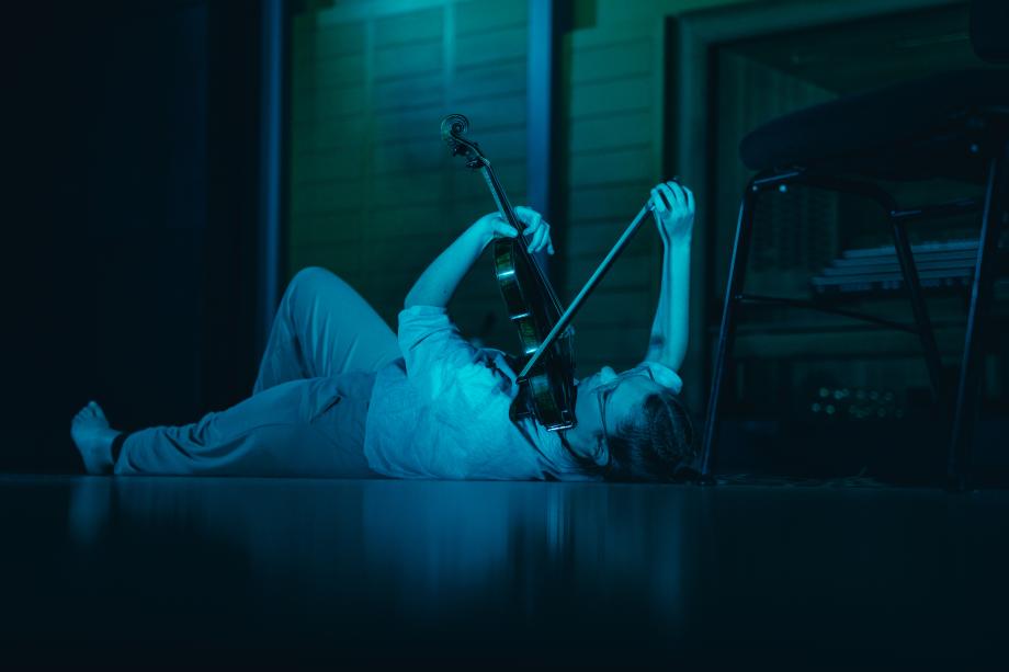 Eine junge Frau spielt Geige, während sie auf dem Boden liegt.