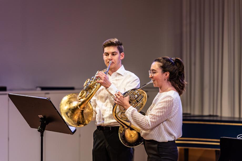 Zwei Horn-Studierende müsizieren auf dem Podium des Orchesterprobenraumes.