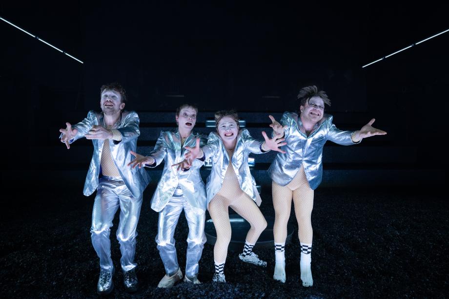 vier silber gekleidete Menschen strecken ihre Arme verzweifelt, glücklich, sehnsüchtig Richtung Fotograf