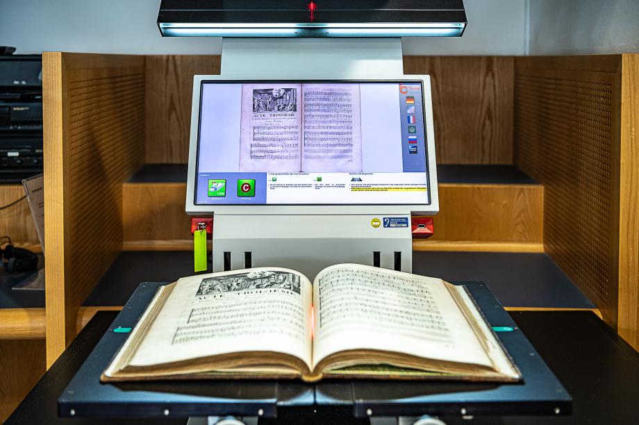 Ein alter Notenband liegt auf einem Buchscanner.