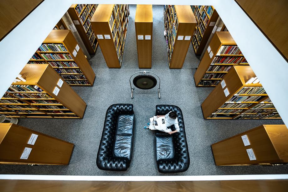Auf dem Bild ist das untere Stockwerk der Bibliothek mit Sofas, Regalen und dem Gong zu sehen.