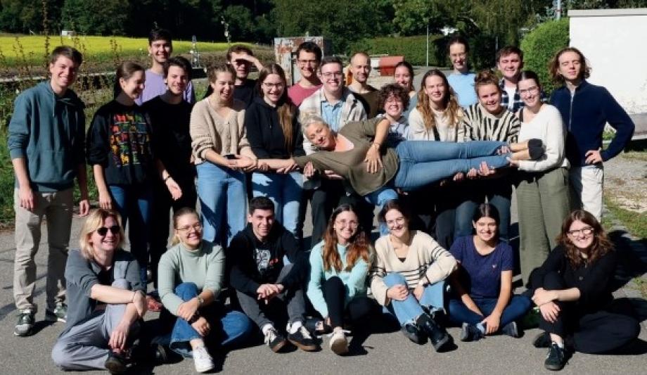 Gruppenfoto von Studierenden, die ihre Dozentin wagerecht vor sich auf den Händen halten.
