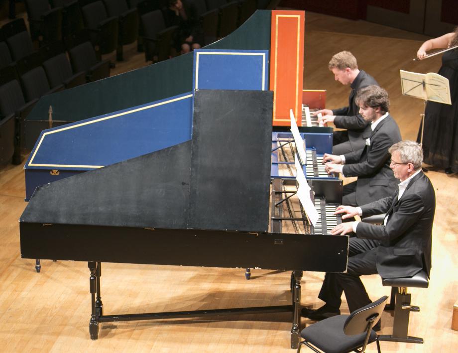Drei Cembalisten musizieren an drei zweimanualigen Cembali.