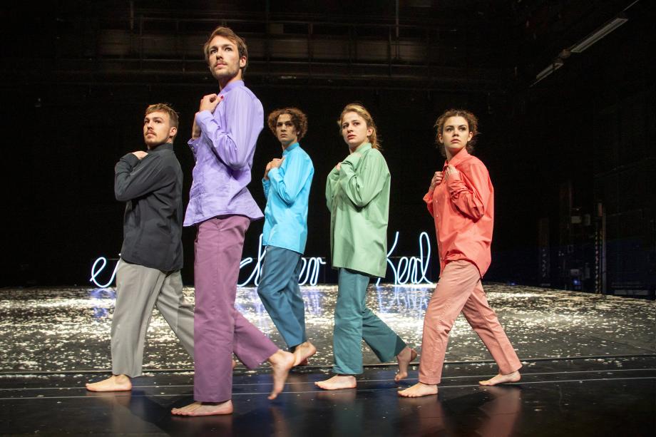 Fünf in je einer Farbe bekleidete Studierende bei einer Schauspielszene.