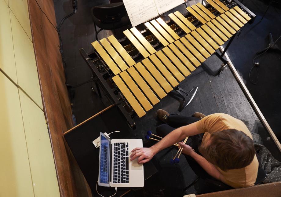 Draufsicht auf Studenten, der auf der Bühne sitzt an einem Laptop. Vor ihm ein Vibraphone.