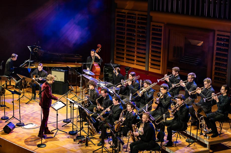 Die Big Band der HMDK Stuttgart unter Leitung von Prof. Rainer Tempel auf dem Konzertsaalpodium.