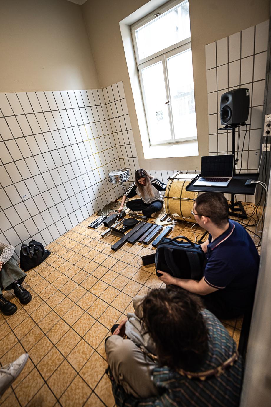 Hell gefließter Raum mit Schlagzeugerin an der Wand. Das Publikum sind unmittelbar neben ihr.