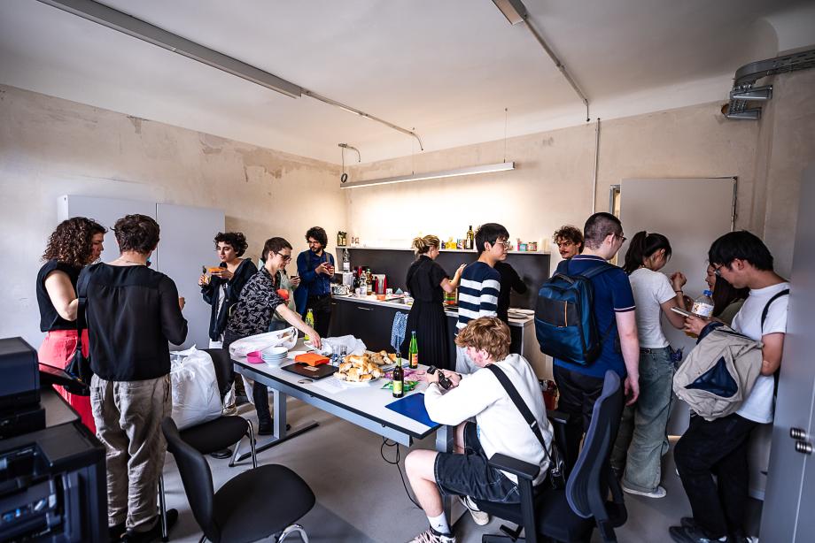 Menschenmenge in der Teeküche. Der Tisch ist gefüllt mit Getränken und Fingerfood.