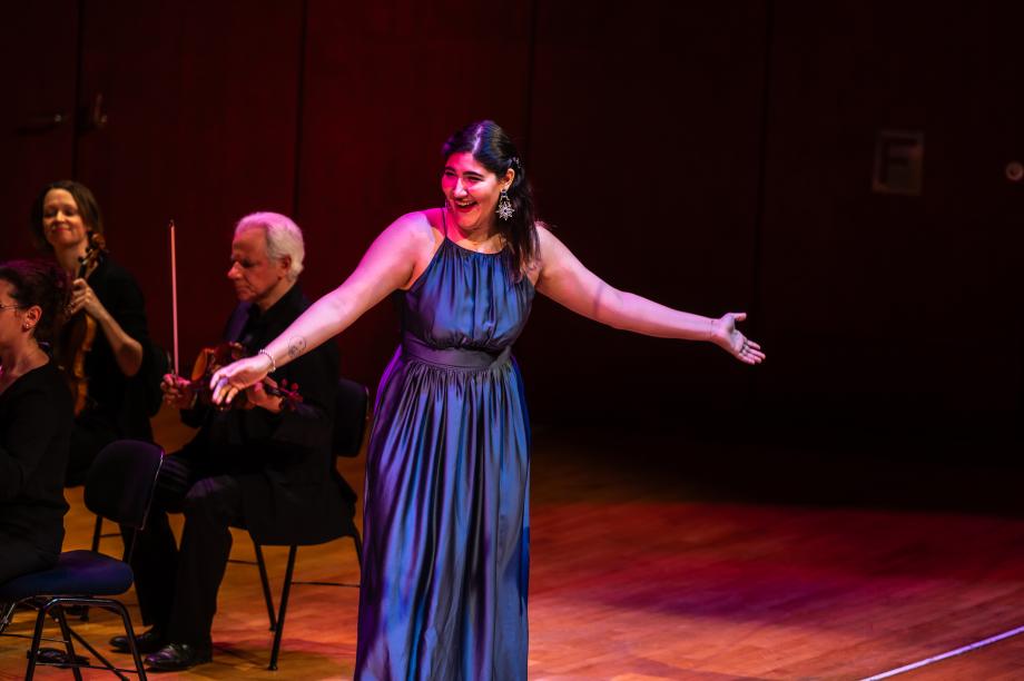 Sängerin im blauen langen Kleid breitet ihre Arme aus.