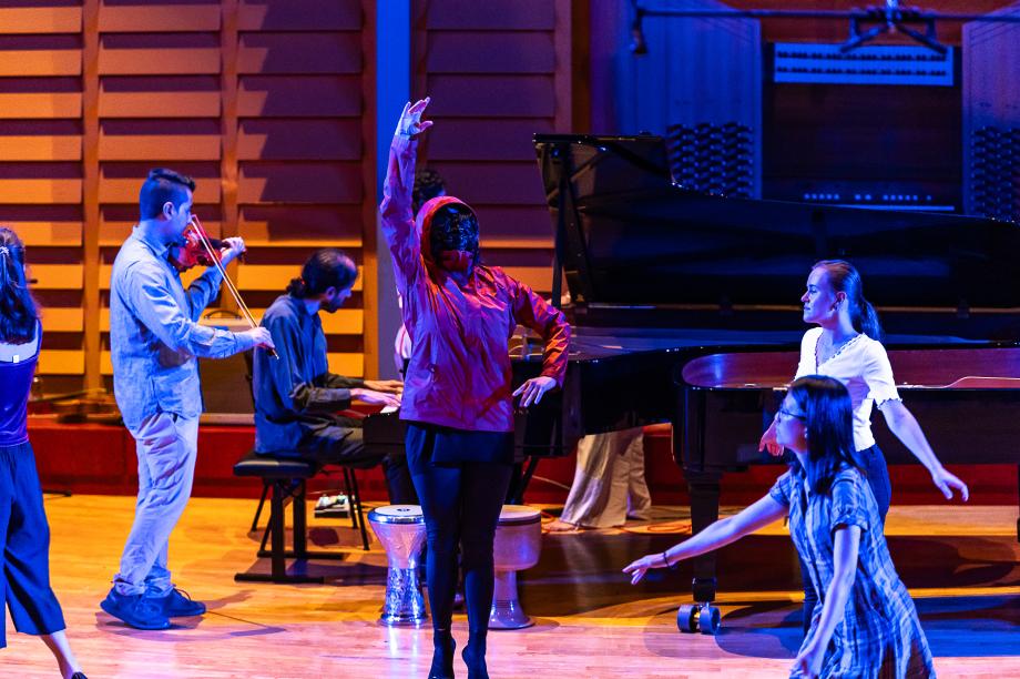 Tanzende Studierende und ein Student an Geige. 