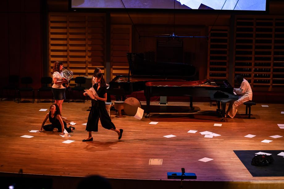 Papier liegt auf dem Boden, zwei Studierende an zwei Flügeln sitzen einander gegenüber.