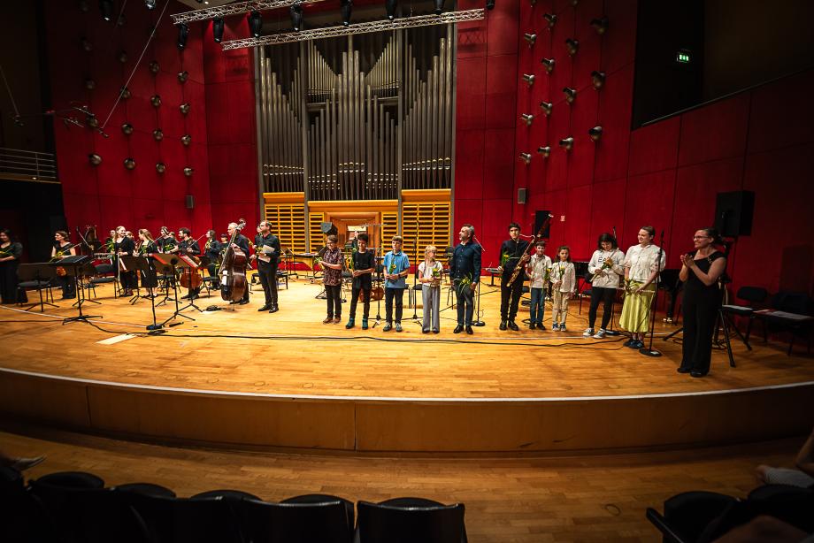 Schlussapplaus mit allen Konzertmitwirkenden beim Antrittskonzert von Prof.in Dr. Karolin Schmitt-Weidmann. Die Mitwirkenden verteilen sich über die gesamte Bühnenbreite des Podiums.