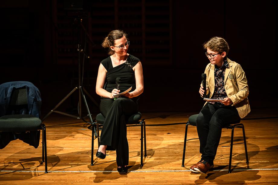 Karolin Schmitt-Weidmann im Gespräch mit ihrem Sohn. Sie ist ihm zugewandt, er schaut auf die Bühnenkante.
