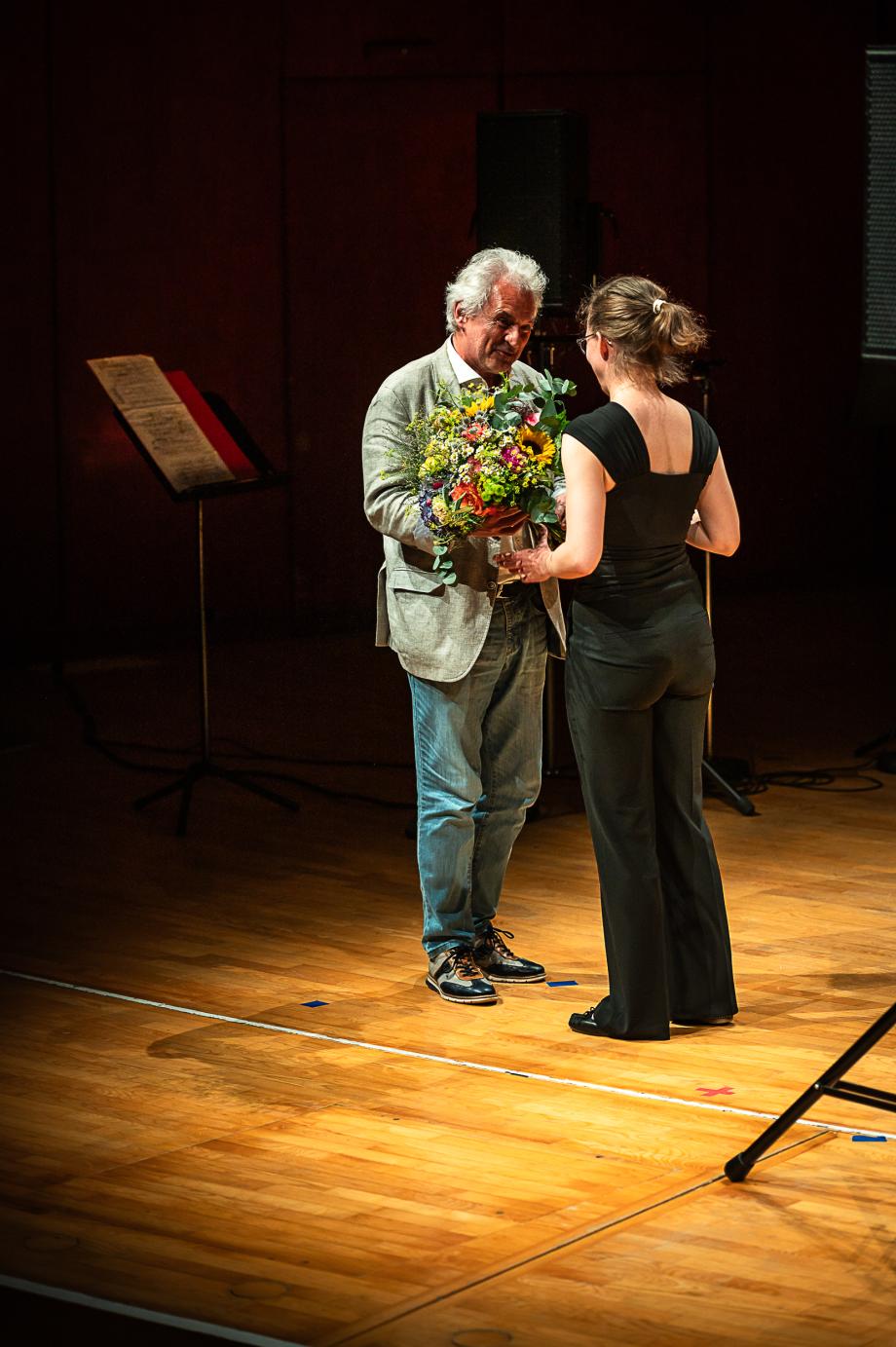 Rektor Axel Köhler überreicht Karolin Schmitt-Weidmann einen sommerlichen, ausladenden Blumenstrauß.