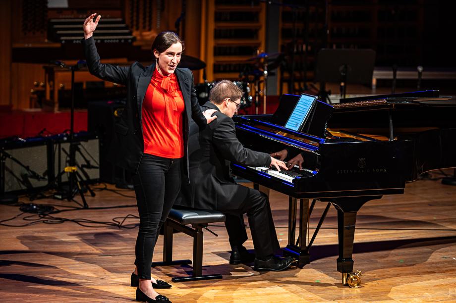 Schulmusikkonzert 2024: Ein Student am Flügel, eine Studentin, die singt und sich mit einer Hand an der Schulter des Pianisten festhält.