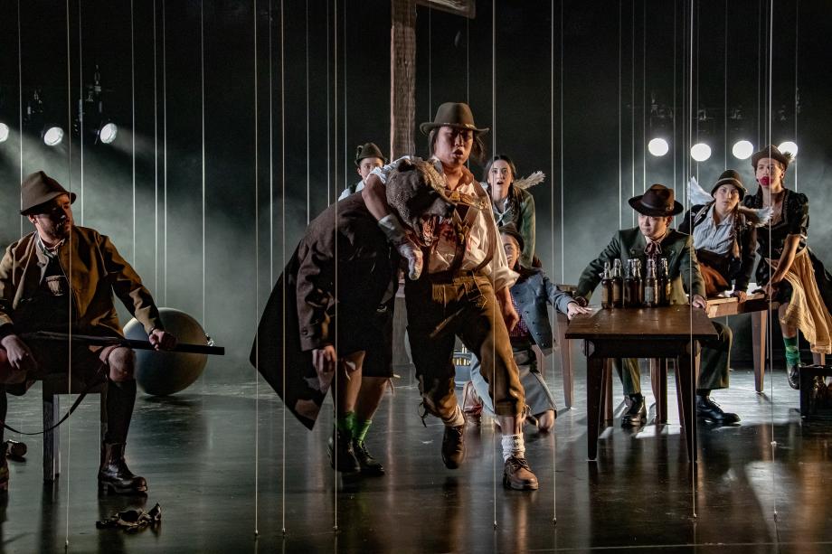 Studierende in einer Bühnenszene mit Trachtengewändern und Lederhosen gekleidet.