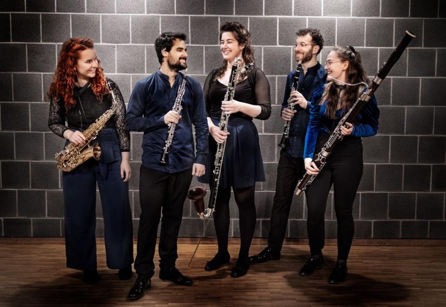 Portraitaufnahme des Sonus Quintettes vor einer grauen Backsteinwand.