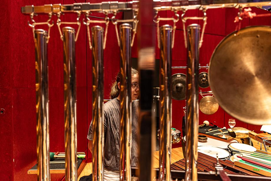 Detailaufnahme von Röhrenglocken. Im Hintergrund sieht man eine Schlagzeugstudentin.