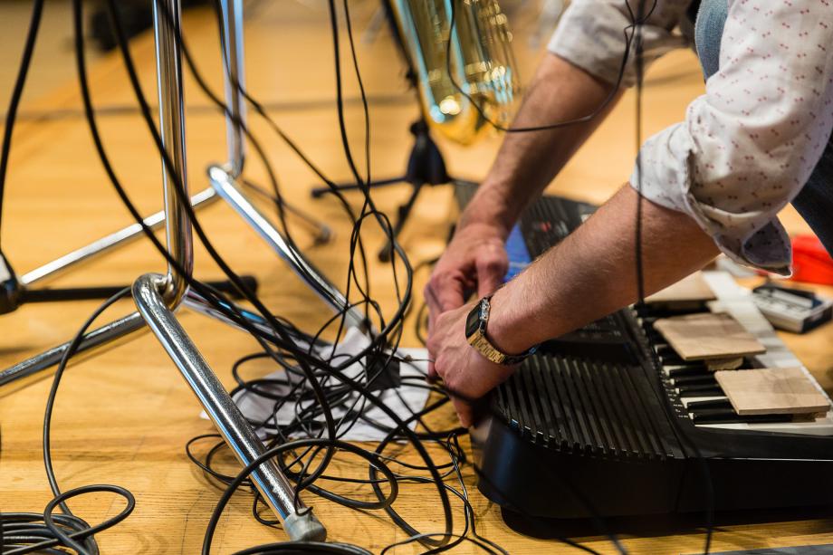 Hände richten Elektronik für Komposition auf Bühnenboden.
