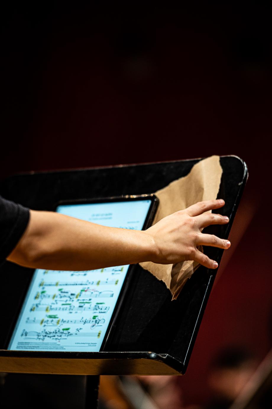 Auf dem Notenpult liegt ein Tablet, daneben führt die rechte Hand ein Schleifpapier.