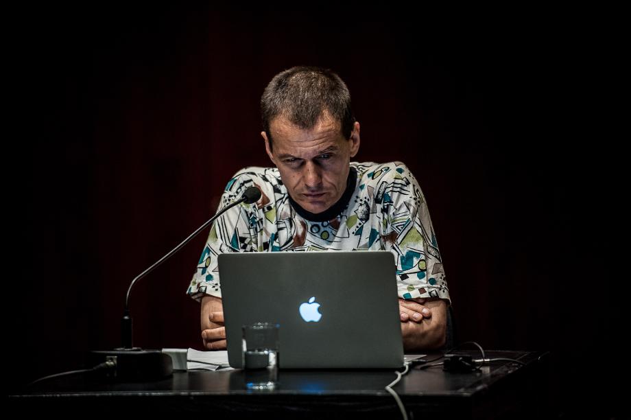 Kompositionsprofessor Maro Stroppa bei einer Podiumsdiskussion. Vor ihm steht ein Laptop.