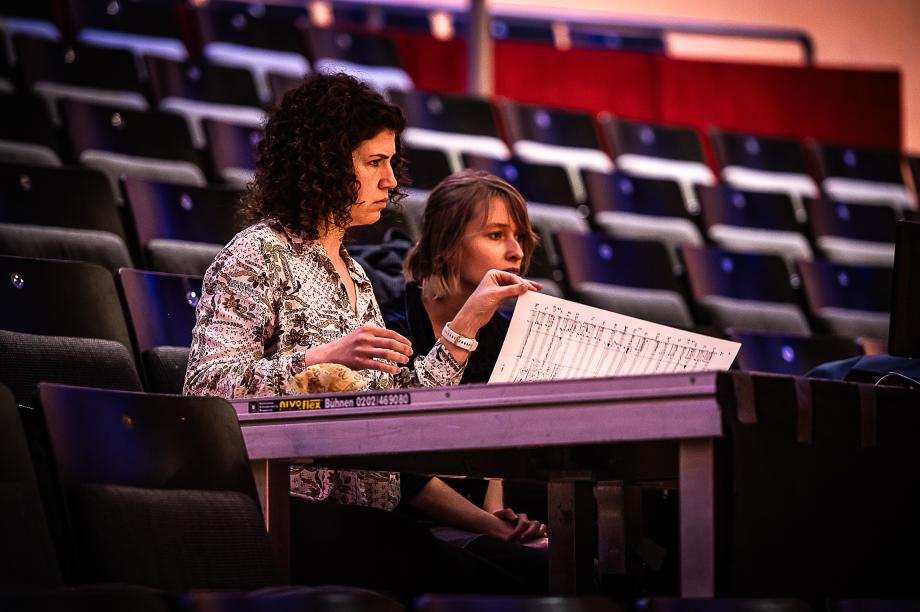 Zwei Studierende verfolgen mit der Partitur am Regie-Pult den Probenprozess im Konzertsaal.