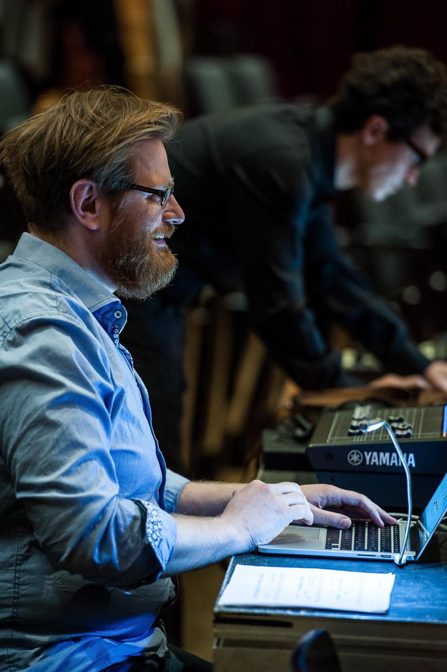 Portraitaufnahme von Prof. Luxa M. Schüttler am Regiepult des Konzertsaales.