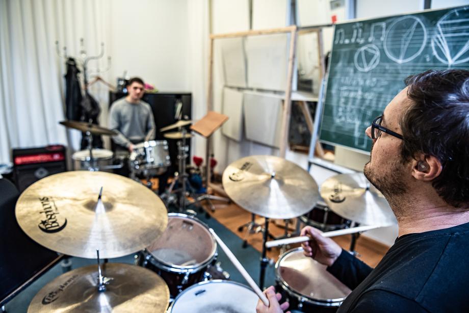 Schlagzeugdozent Eckhard Stromer im Dialog mit Student, beide an ihrem Setup sitzend und Blickkontakt haltend.