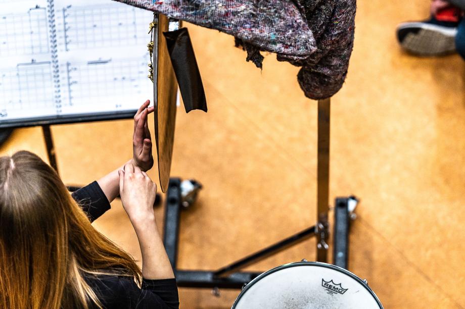 Von oben beobachtete Schlagzeugstudentin, den Blick auf das Notenpult gerichtet und mit zwei Fingern das Becken spielend.