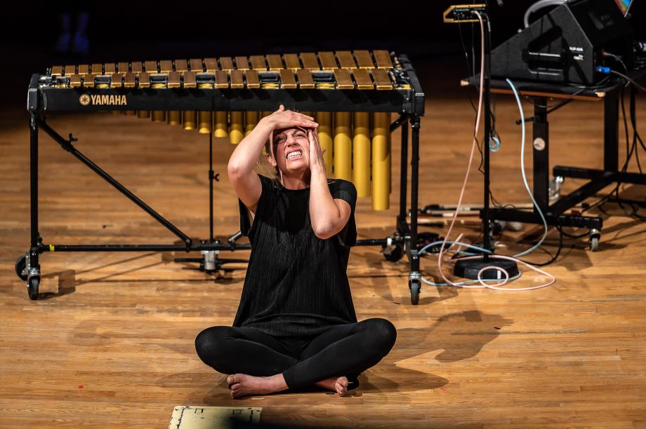 Vanessa Porter sitzt barfuß auf Boden im Schneidersitz, ihr Gesicht ist verzerrt und sie hält sich mit beiden Händen das Gesicht.
