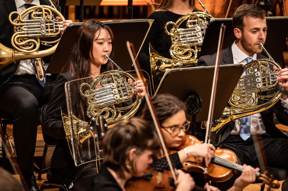 Detailausschnitt der Horngruppe des HochschulSinfonieOrchesters. Im Vordergrund sind noch der Studierende der Streicherklassen zu erkennen.