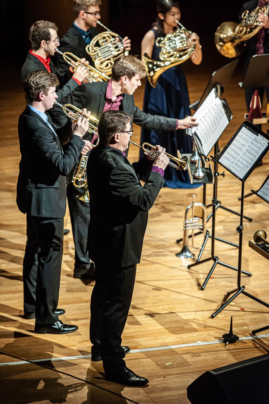 Prof. Wolfgang Bauer und weitere Studierende der Trompetenklasse beim gemeinsamen Musizieren des Ensembles City Brass. Die Studierende sind in Anzug gekleidet und tragen unterschiedlich farbige Hemden.