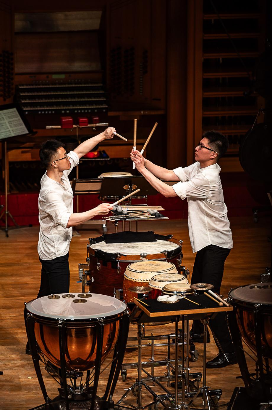 Schlagzeugstudierende schlagen erhobene Schlägel aneinander. Eine trennung erfahren sie durch einen Schlagaufbau.