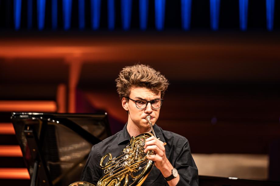 Detailaufnahme eines Hornstudierenden im Konzertsaal.