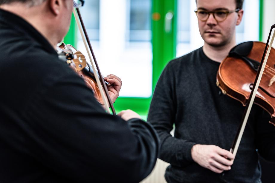 Violaprofessor mit einem Studierenden. Der Studierende verfolgt fokussiert dem Vorspiel.