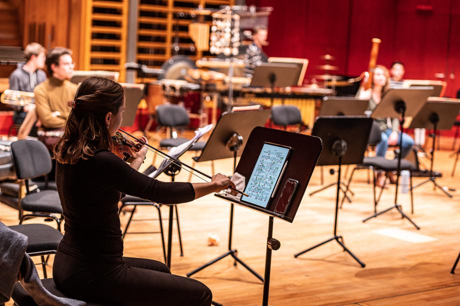 Geiegnstudentin beim Musizieren. Auf dem Notenpult liegt ein Tablet und ein Smartphone.